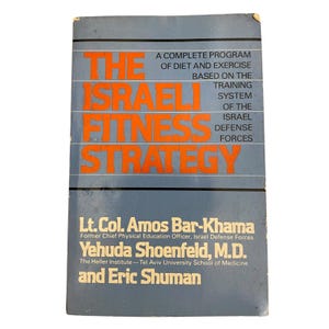 Puede incluir: Un libro antiguo titulado "The Israeli Fitness Strategy" con una cubierta azul y letras naranjas. El libro detalla un programa completo de dieta y ejercicio basado en el sistema de entrenamiento de las Fuerzas de Defensa de Israel. Autores: Lt. Col. Amos Bar-Khama y Yehuda Shoenfeld, M.D.