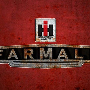 May include: A rusty red metal sign with the words "FARMALL" in black letters and a smaller red and white logo that says "INTERNATIONAL HARVESTER" above it.