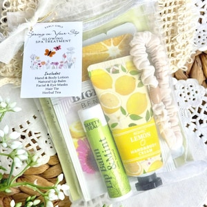 May include: A clear bag containing spa treatment items. Includes a hand and body lotion, lip balm, facial and eye masks, hair tie, and herbal tea. The lotion tube has a lemon design. A tag reads "Spring in Your Step" and "Glowing Spa Treatment."