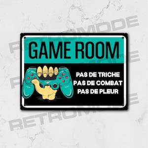 Puede incluir: Un letrero negro y turquesa con el texto "GAME ROOM" en letras blancas. Un mando de videojuego verde está en el centro del letrero con una mano que lo sostiene. El texto "PAS DE TRICHE PAS DE COMBAT PAS DE PLEUR" está debajo del mando.