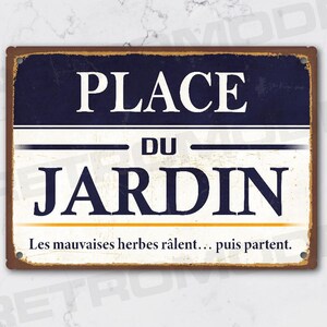 May include: A rectangular metal sign with a distressed finish. The sign features the words "PLACE DU JARDIN" in white, with a navy blue top section and a cream-colored bottom section. The text "Les mauvaises herbes râlent... puis partent." is at the bottom.