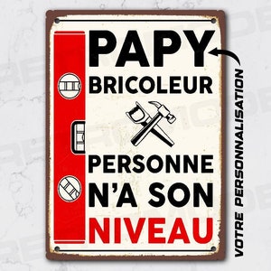 Peut inclure: Une pancarte blanche et rouge avec le texte "Papy Bricoleur Personne n'a son Niveau" et une image d'un marteau et d'une scie. La pancarte est conçue pour ressembler à une pancarte en métal vintage.