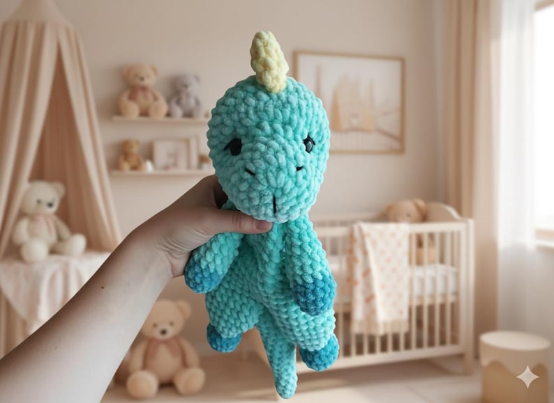 May include: A handmade turquoise crochet dinosaur plush toy with a light yellow horn. The dinosaur has dark blue accents on its feet and tail. The toy is soft and cuddly, perfect for a child's nursery or playroom.