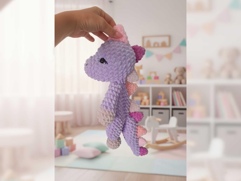 May include: A handmade, lavender crochet dinosaur toy with pink and peach accents. The plush toy has a soft, textured appearance, with small black eyes and a pink horn. The dinosaur's back features a row of pink and peach spikes. A charming, whimsical children's toy.