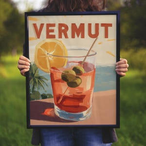 Può includere: Una stampa artistica rettangolare incorniciata con la parola VERMUT in lettere arancioni in grassetto. L'illustrazione raffigura un bicchiere di cocktail rosso con due olive verdi su uno stecchino e una fetta d'arancia gialla.