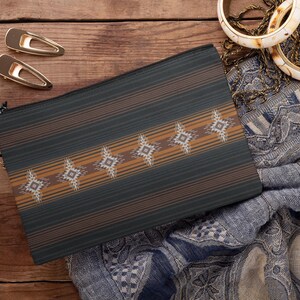 May include: A dark green and brown patterned zippered pouch with a geometric design. Two gold hair clips and two ivory and gold bangles are also visible. The pouch is on a wooden surface.