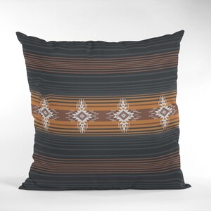May include: Square throw pillow with a Southwestern design. The pillow features a dark gray background with horizontal brown and orange stripes. A central band showcases geometric patterns in white, brown, and orange.
