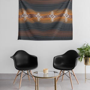 May include: A dark gray tapestry with horizontal orange and brown stripes and four geometric designs. The tapestry is hanging on a white wall above two black chairs and a small glass table.