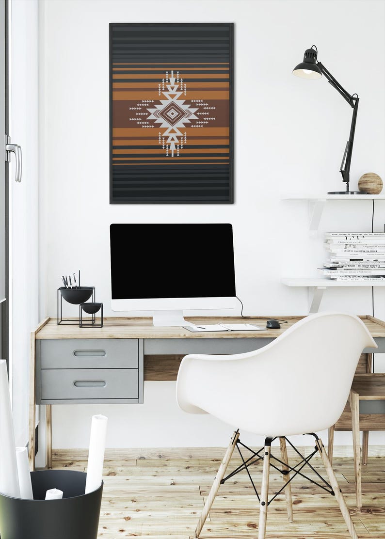 May include: A framed wall art print featuring a geometric design in shades of brown, white, and gray, set against a backdrop of horizontal black and brown stripes. The artwork hangs above a wooden desk with a computer and a white chair.