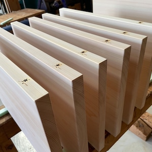 May include: A stack of eight light wood cutting boards with a Japanese character burned into the surface of each board.