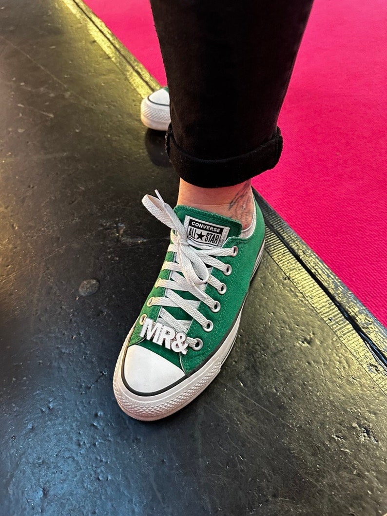 Weiße Braut Schuhclips für Hochzeit auf grünen Converse All Star Turnschuhen. Weiße MR& MRS Schuhclips mit silbernen Metallrahmen. Hochzeitsschuhe für Braut mit Schuhclips. Sneaker für Wedding.