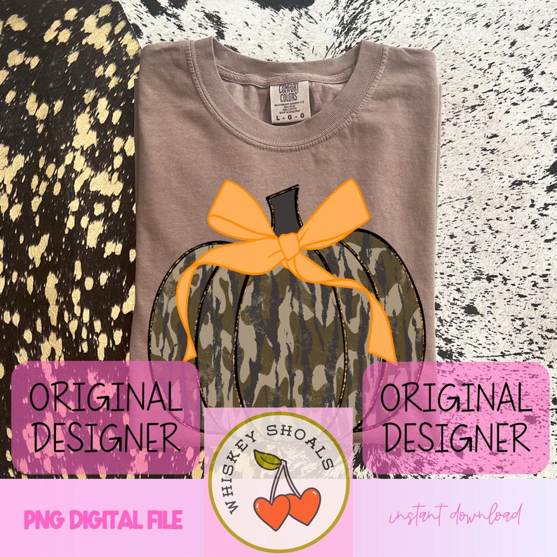 Peut inclure: Un t-shirt Comfort Colors beige avec un motif de citrouille camouflage et un n&oelig;ud orange. Le t-shirt porte les inscriptions "Whiskey Shoals" et "Original Designer".