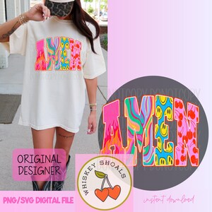 Puede incluir: Camiseta color crema con la palabra "AMEN" en un dise&ntilde;o psicod&eacute;lico colorido. Las letras presentan remolinos, llamas, caras sonrientes y cerezas. Tambi&eacute;n es visible un logotipo redondo con cerezas y el texto "Whiskey Shoals".