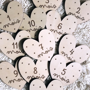 Peut inclure: Marqueurs d'étapes en forme de cœur en bois avec des chiffres et le mot « mois » ou « an » en écriture manuscrite. Chaque cœur a de petits accents en forme de cœur. Les marqueurs servent à suivre l'âge d'un bébé.