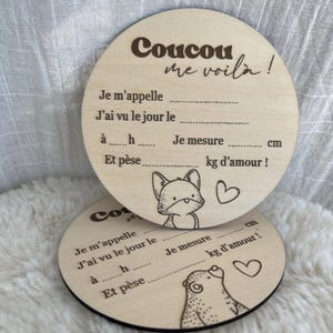 Peut inclure: Deux disques en bois gravés au laser pour annoncer une naissance. Le disque supérieur présente une illustration de renard et le texte Coucou me voilà, avec des lignes pointillées pour le nom, la date, l'heure, la taille en cm et le poids en kg.