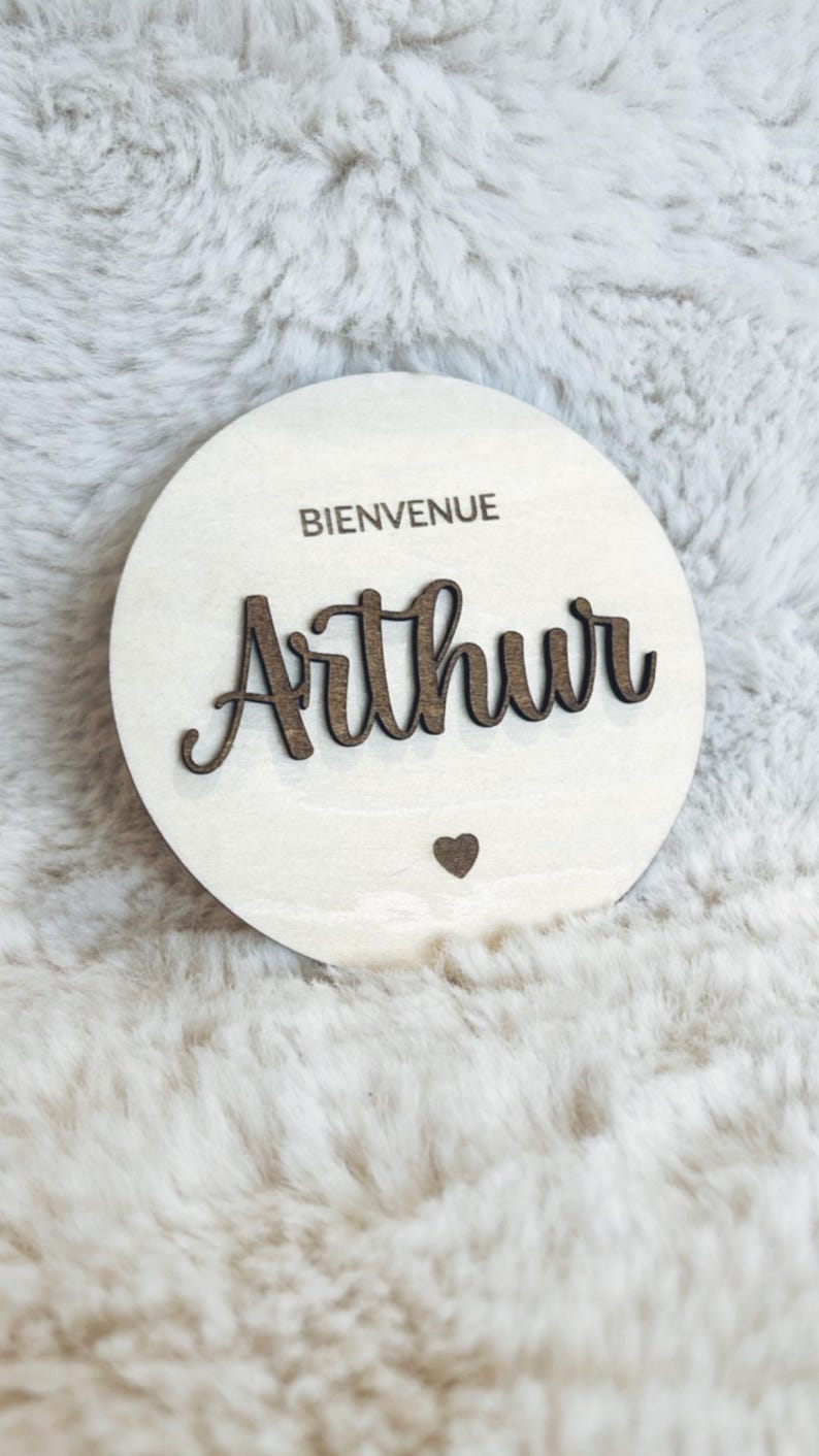 May include: A round wooden sign with the text "Bienvenue" and the name "Arthur" in cursive script. A small heart is below the name.