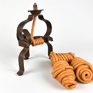 May include: A vintage brown metal candle holder with a small candle and three orange wax coils. The candle holder has a decorative, ornate design with a circular frame and three legs.