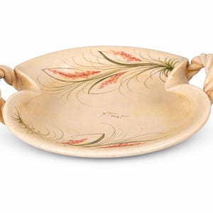 May include: Cream-colored ceramic serving dish with two rope-style handles. The dish features a floral design in red and green. The dish is oval-shaped and has a slightly raised edge.