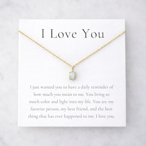 May include: A gold-colored necklace with a small, rectangular, light-colored pendant. The necklace is displayed on a white card with the text "I Love You" and a loving message.