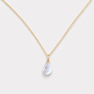 May include: A delicate gold chain necklace featuring a single, translucent, teardrop-shaped gemstone pendant. The stone is secured with gold wire wrapping at the top, creating a simple, elegant drop design that hangs centrally from the fine metal links.