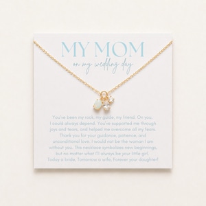 May include: A gold chain necklace with two small charms, one oval and one round, displayed on a white card. The card features the text MY MOM on my wedding day and a printed message expressing gratitude, ending with Today a bride, Tomorrow a wife, Forever your daughter.