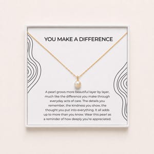 Puede incluir: Un collar de cadena dorada con un colgante de perla blanca presentado en una tarjeta blanca. La tarjeta incluye el texto YOU MAKE A DIFFERENCE y un párrafo sobre perlas y bondad, enmarcado por líneas negras en los lados izquierdo y derecho.