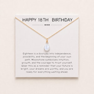 May include: A gold-tone chain necklace with a teardrop-shaped moonstone pendant, displayed on a white card printed with the text HAPPY 18TH BIRTHDAY and a message about independence, growth, and the future, featuring three small black hearts.