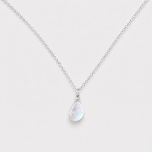 May include: A silver chain necklace featuring a single teardrop-shaped moonstone pendant. The translucent, iridescent stone is secured with a silver wire wrap at the top, connecting it to a delicate, polished silver link chain.