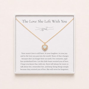 May include: A gold chain necklace with a heart-shaped opal pendant surrounded by small clear stones. The necklace is displayed on a white card featuring the text The Love She Left With You and a message about a mother's love and memory.