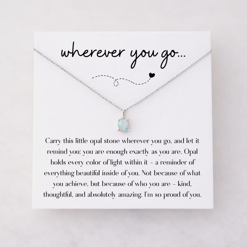 Puede incluir: Un collar de plata con un peque&ntilde;o colgante de &oacute;palo azul claro. El colgante cuelga de una delicada cadena. La tarjeta detr&aacute;s del collar tiene las palabras "wherever you go..." y un mensaje sobre la autoestima.