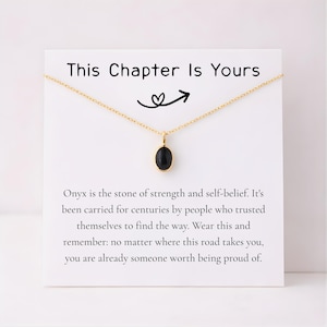 May include: Gold-colored necklace with a black onyx stone pendant. The necklace hangs on a white card with the text "This Chapter Is Yours" and inspirational text about strength and self-belief.