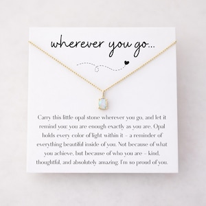 Può includere: Una collana dorata con un pendente di opale rettangolare su una carta bianca. La carta riporta la scritta "wherever you go..." e un messaggio sul valore di sé. Un gioiello delicato.