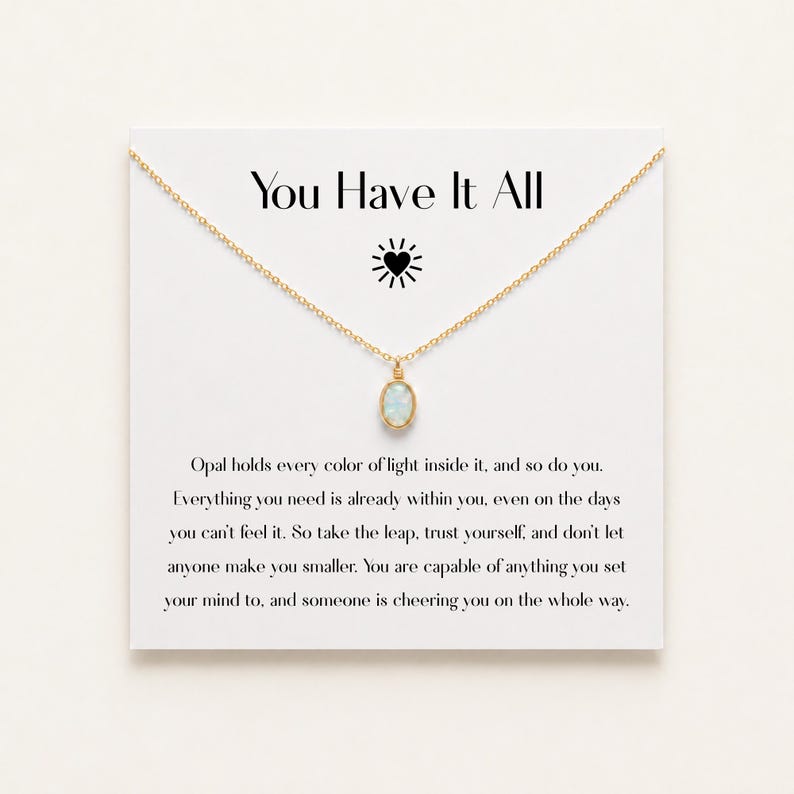 May include: A gold chain necklace with an oval opal pendant displayed on a white card featuring the text You Have It All, a sun icon, and a paragraph about opal light. The necklace is centered on the card, which provides a message of encouragement.