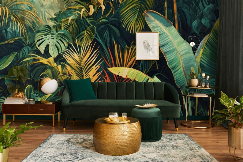 Peut inclure: Un canap&eacute; en velours vert avec des pieds dor&eacute;s est plac&eacute; devant une fresque murale repr&eacute;sentant une jungle tropicale. Une table basse ronde dor&eacute;e avec une finition martel&eacute;e et un ottoman en velours vert se trouvent devant le canap&eacute;. Une table d'appoint dor&eacute;e avec un plateau en verre et une plante en pot se trouvent &agrave; droite du canap&eacute;.