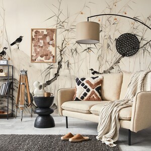 Puede incluir: Un sal&oacute;n de tonos neutros con un sof&aacute; beige, cojines estampados y una manta tejida. La habitaci&oacute;n incluye una estanter&iacute;a de metal negro, una mesa auxiliar y un gran mural con p&aacute;jaros y bamb&uacute;. Una l&aacute;mpara de pie negra y una cesta tejida tambi&eacute;n est&aacute;n presentes.