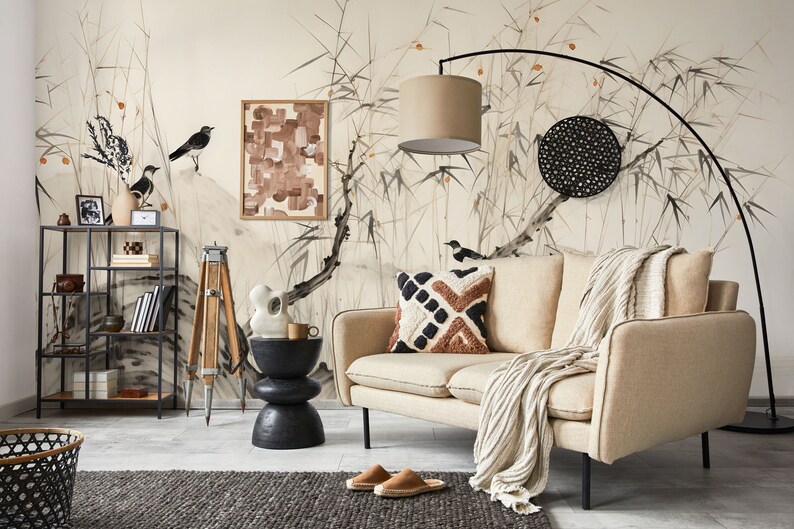 Puede incluir: Un sal&oacute;n de tonos neutros con un sof&aacute; beige, cojines estampados y una manta tejida. La habitaci&oacute;n incluye una estanter&iacute;a de metal negro, una mesa auxiliar y un gran mural con p&aacute;jaros y bamb&uacute;. Una l&aacute;mpara de pie negra y una cesta tejida tambi&eacute;n est&aacute;n presentes.