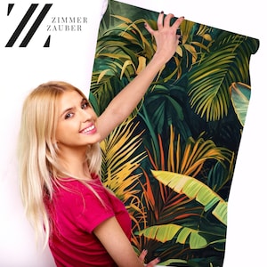 Peut inclure: Une femme tient un rouleau de papier peint &agrave; motifs de feuilles tropicales. Le papier peint pr&eacute;sente un motif de jungle aux couleurs vives, vert, jaune et orange.