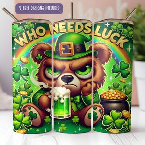 Op de afbeelding: Een set van drie roestvrijstalen bekers met een thema voor St. Patrick's Day. Elke beker heeft een cartoonbeer met een groene leprechaun-hoed, een regenboog, klavers en de tekst "WHO NEEDS LUCK".