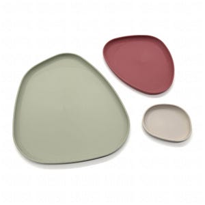 May include: Three irregularly shaped plates in muted colors: sage green, dusty rose, and beige. The plates have a smooth surface and a slightly raised edge. The arrangement suggests a set of serving dishes or decorative items.