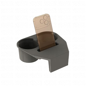 May include: A dark grey plastic cup holder insert featuring two circular compartments and a central rectangular slot designed to hold a smartphone upright. The device is positioned vertically within the slot, displaying a translucent brown frame.