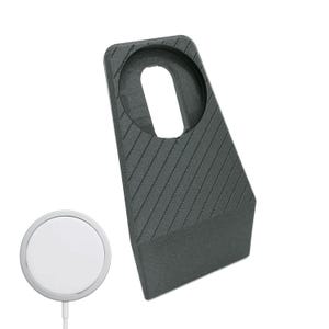 Pode incluir: Um suporte de plástico preto com uma superfície texturizada e um recorte circular para uma plataforma de carregamento sem fio. O suporte é projetado para segurar um relógio inteligente ou outro dispositivo para carregar.