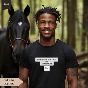 Może przedstawiać: Czarny T-shirt z nadrukiem "EVERYTHING IS UNDER Ctrl" z przodu. Koszulkę nosi osoba z dredami stojąca w lesie.