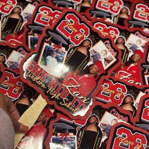 May include: A collection of red and black graduation stickers. Each sticker features a photo of a graduate, the text "Class of 23", and the words "She Did It!" and "Western High School".