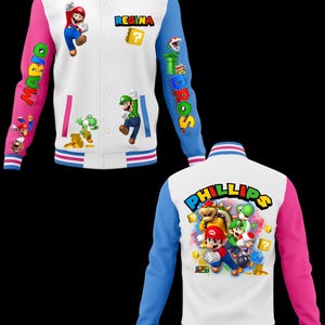 Puede incluir: Una chaqueta tipo varsity blanca con mangas rosas y azules, con gr&aacute;ficos de personajes de Super Mario, el nombre REGINA en el frente y el nombre PHILLIPS en la espalda. El dise&ntilde;o incluye a Mario, Luigi, Yoshi, Bowser y Toad con iconos.