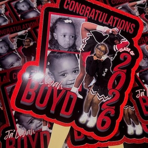 May include: A collection of graduation fan decorations. Each fan features a photo of a young person, the name "Ja'Liyah Boyd", and the text "Congratulations Class of 2026" in red and black.