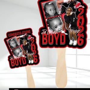 May include: Two graduation fan decorations. Each fan features a photo of a child, the name "Ja'Liyah Boyd", and the text "Congratulations" and "Class of 2026" in red and black. The fans have wooden handles.