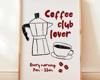 May include: A framed print with a coffee theme. The artwork features a black and white illustration of a coffee maker and a cup of coffee. The text "Coffee club lover" and "Every morning 7am - 11am" are in red.