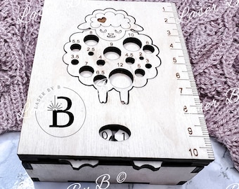 May include: Wooden box with a sheep-shaped cutout for storing knitting needles. The box has a ruler on the side and a label that says "Laser By B".