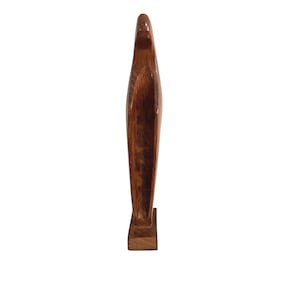 May include: A tall, abstract wooden sculpture with a smooth, polished finish. The sculpture is a rich, warm brown color and stands on a rectangular base. The design is elongated and streamlined, suggesting a modern aesthetic.