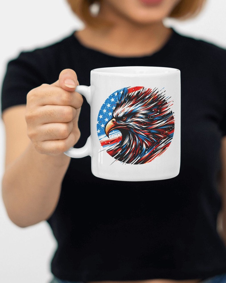 May include: White ceramic mug with a graphic of an eagle's head in front of an American flag. The eagle's head is red, white, and blue.